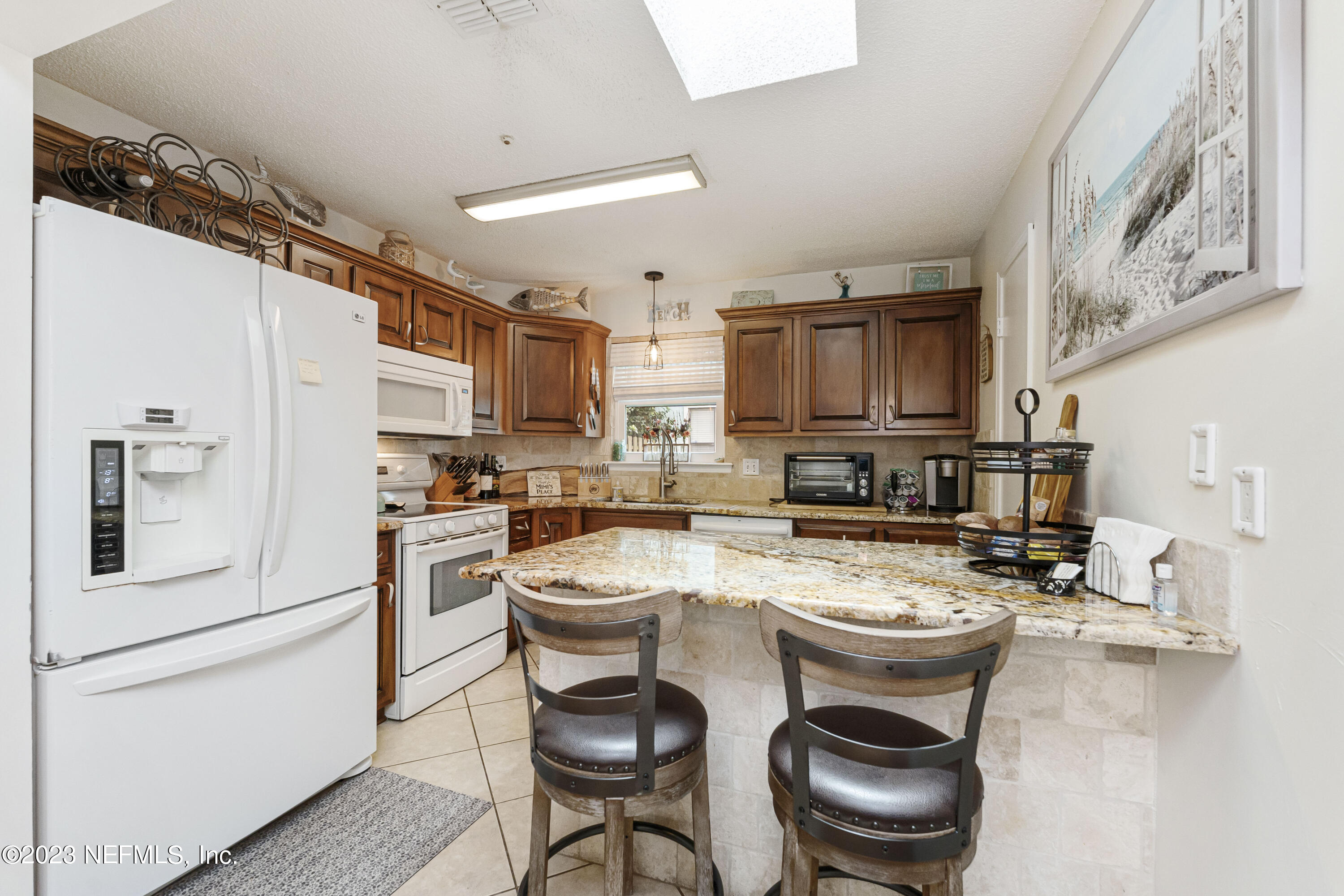 1676 Westwind Drive Jacksonville Beach, FL 32250 - Photo 8 of 42 a kitchen with stainless steel appliances granite countertop a refrigerator a stove a sink a dining table and chairs with wooden floor