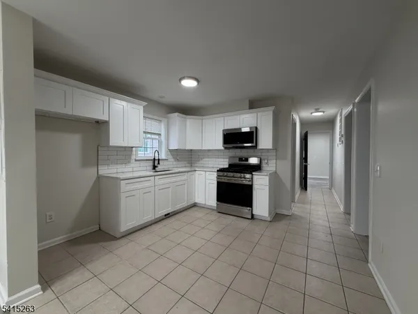 a kitchen with granite countertop a sink a counter top space stainless steel appliances and cabinets