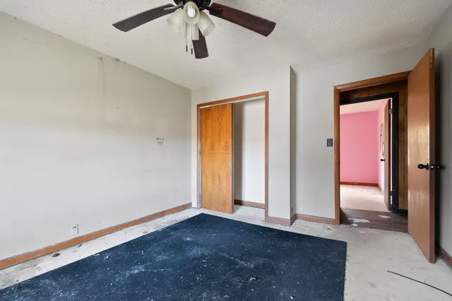 an empty room with closet and a chandelier fan