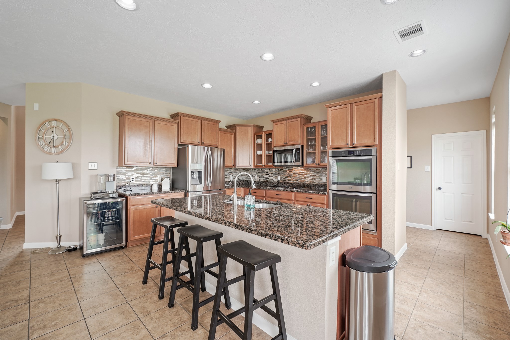 2502 J. R. Drive Manvel, TX 77578 - Photo 9 of 31 a kitchen with kitchen island granite countertop wooden cabinets and a refrigerator