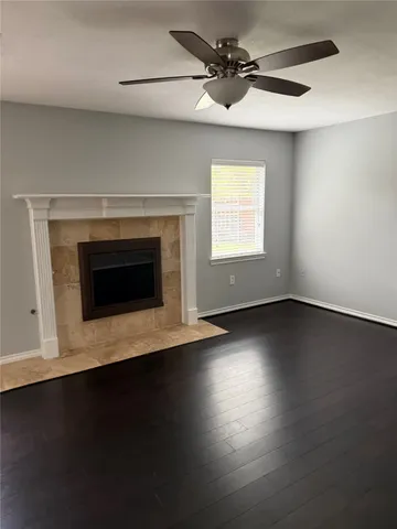 an empty room with wooden floor fireplace and windows
