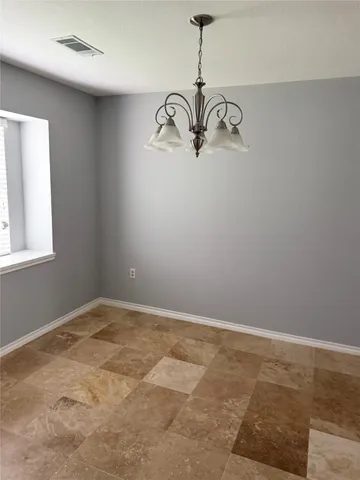 a view of a room that has a chandelier fan and wooden floor