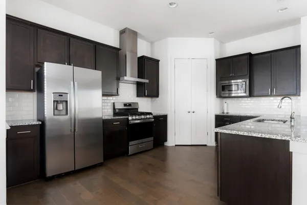 a kitchen with granite countertop a refrigerator and a stove top oven
