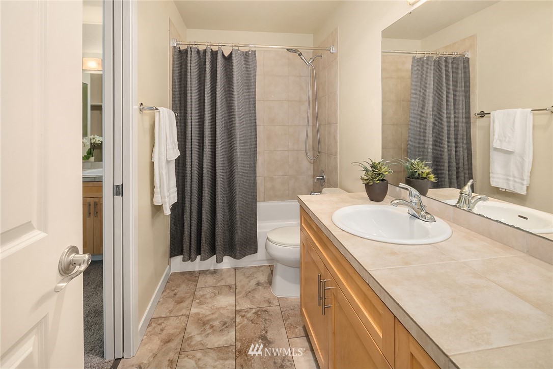 3926 243rd Place Southeast, Unit H301 Bothell, WA 98021 - Photo 10 of 16 a bathroom with a granite countertop sink a mirror and a shower