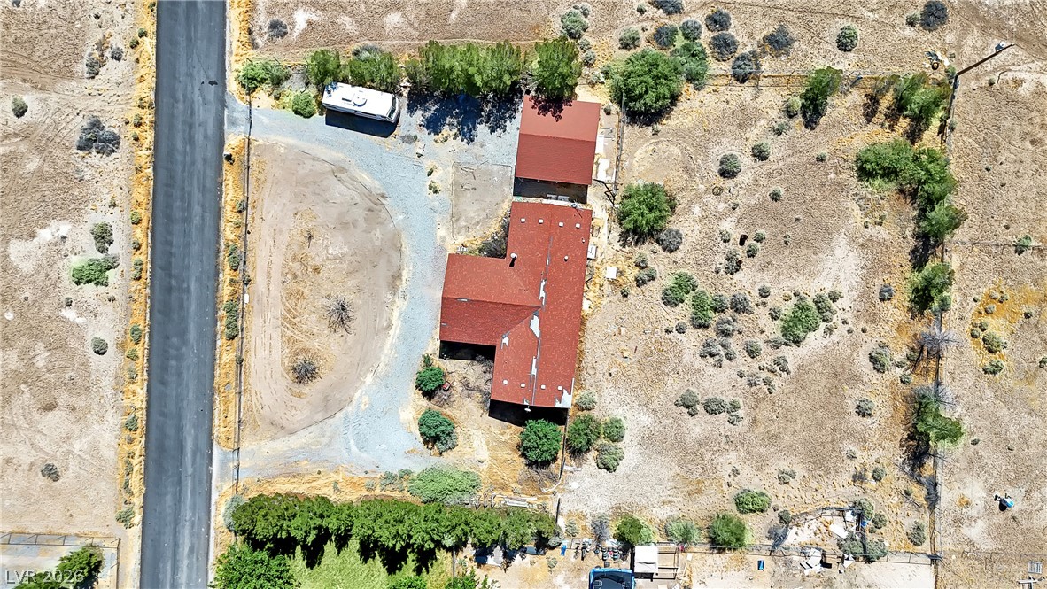 4361 Maple Road Pahrump, NV 89048 - Photo 2 of 46 An aerial perspective reveals a secluded estate featuring a residence with a red roof, embraced by arid terrain.