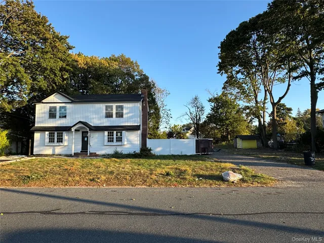 a view of a house with a large tree and a yard in front of it