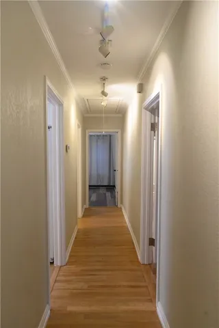 a view of a hallway with wooden floor and a bathroom