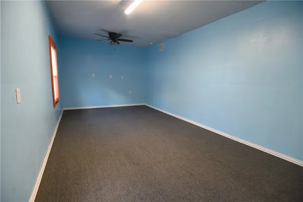 an empty room with a ceiling fan and a window