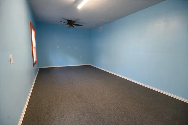 an empty room with a ceiling fan and a window