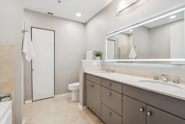 a bathroom with a double vanity sink toilet and a mirror
