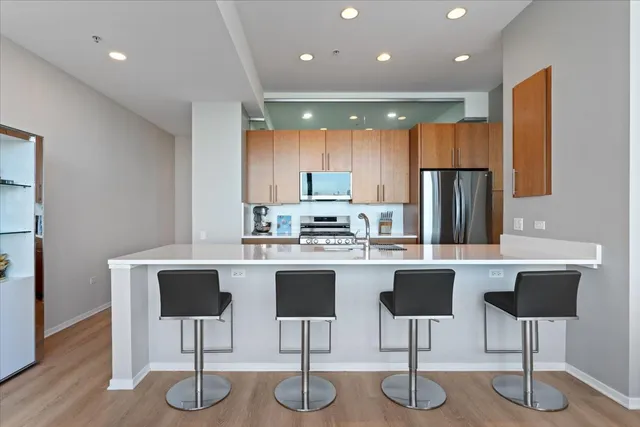 a kitchen with stainless steel appliances granite countertop a dining table chairs refrigerator sink and cabinets