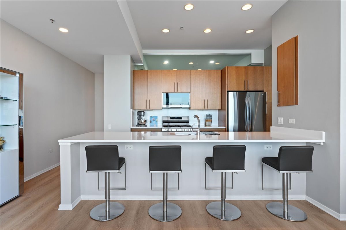 500 West Superior Street, Unit 802 Chicago, IL 60654 - Photo 5 of 28 a kitchen with stainless steel appliances granite countertop a dining table chairs refrigerator sink and cabinets