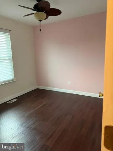 en empty room with wooden floor and windows