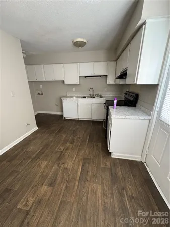 a kitchen with a wooden floor and white cabinets