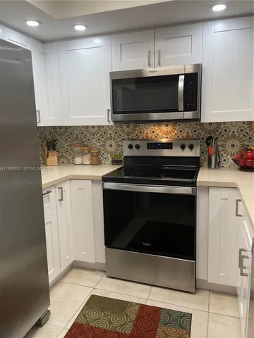 a kitchen with stainless steel appliances a sink a stove a microwave a sink and a refrigerator