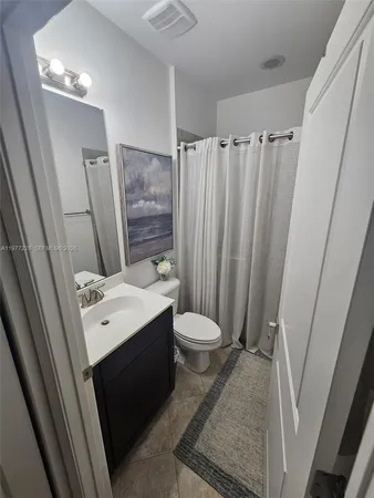 a bathroom with a sink a toilet a mirror and shower curtain