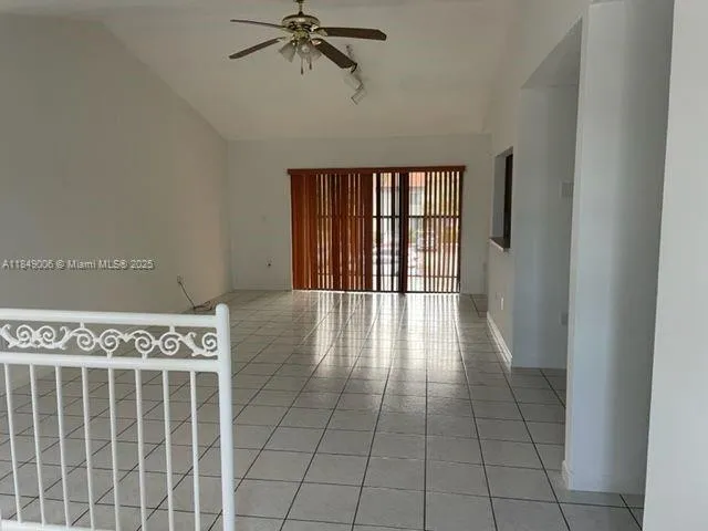an empty room with chandelier fan and windows
