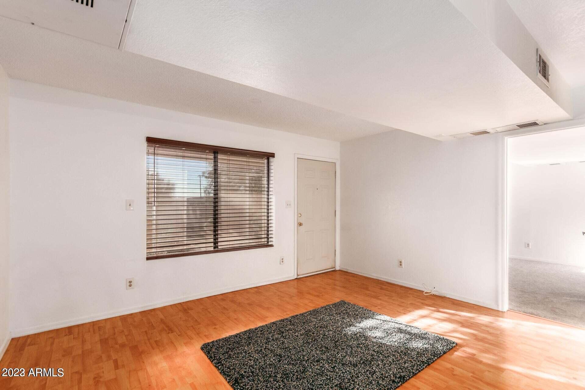 1440 North Idaho Road, Unit 1036 Apache Junction, AZ 85119 - Photo 4 of 13 a view of empty room with wooden floor and window