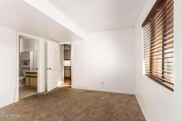 a view of an empty room with kitchen and a window
