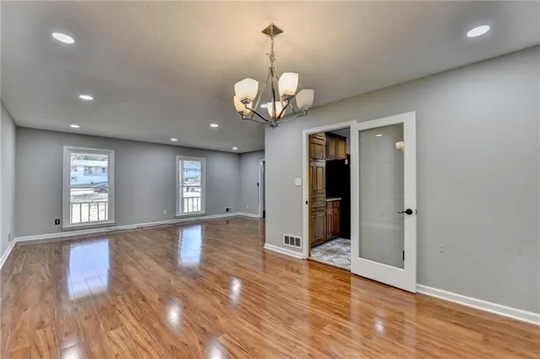 a view of an empty room with wooden floor and windows