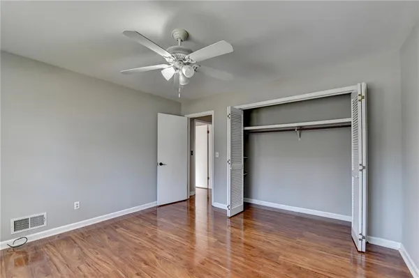 an empty room with wooden floor closet and windows