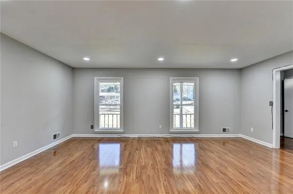an empty room with wooden floor and windows