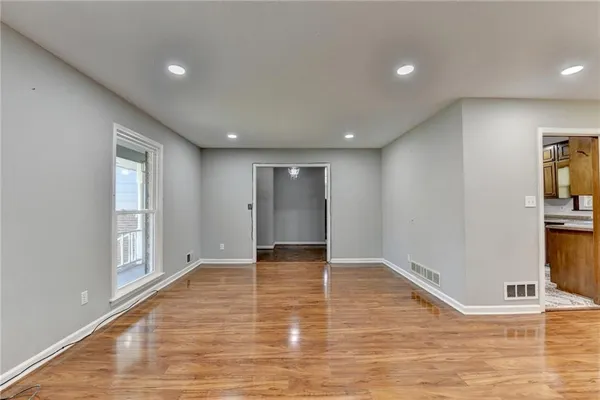 a view of an empty room with wooden floor and a window