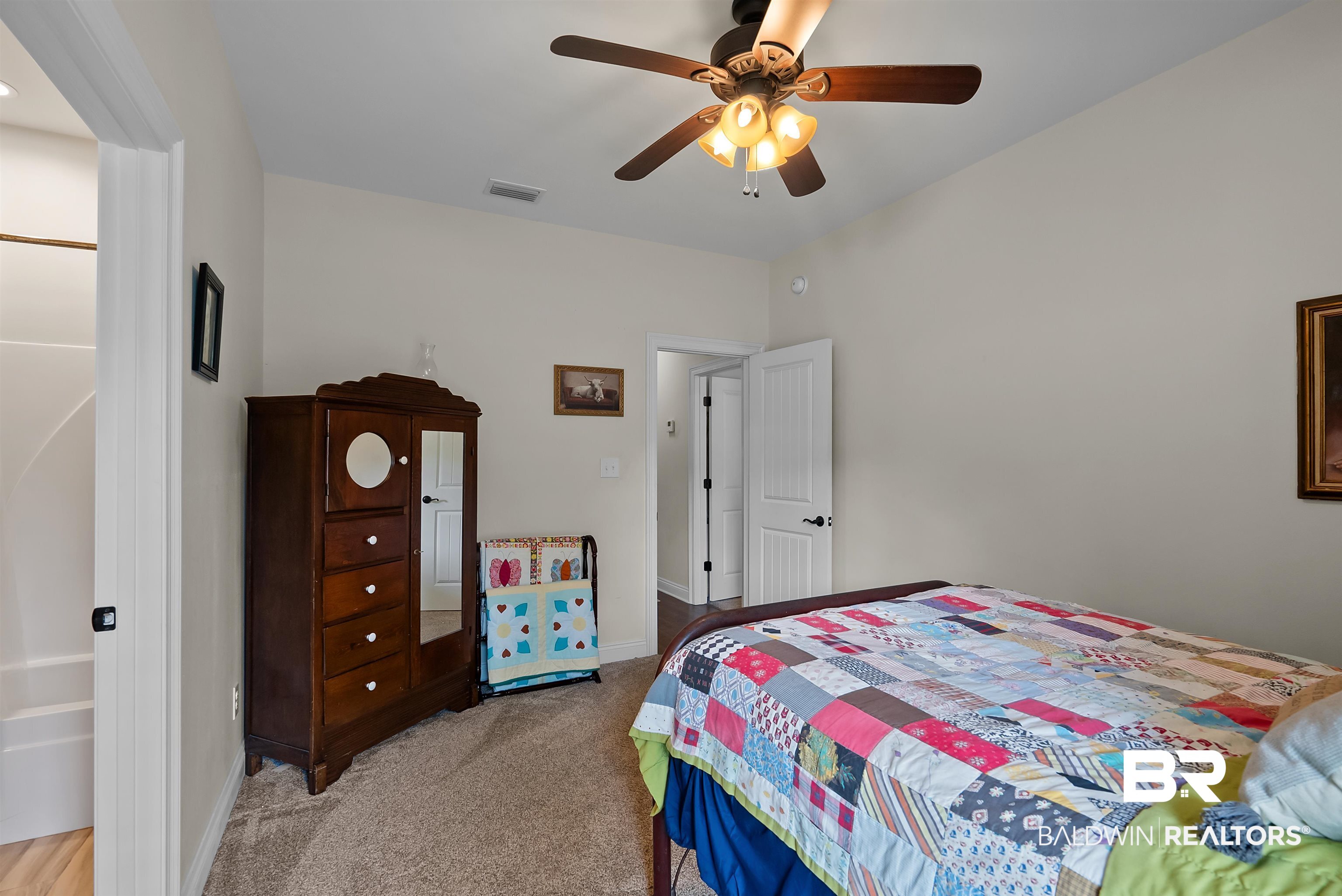 12070 Comalander Road Fairhope, AL 36532 - Photo 27 of 50 Carpeted room featuring a ceiling fan with integrated lighting, a white paneled door, and neutral wall paint