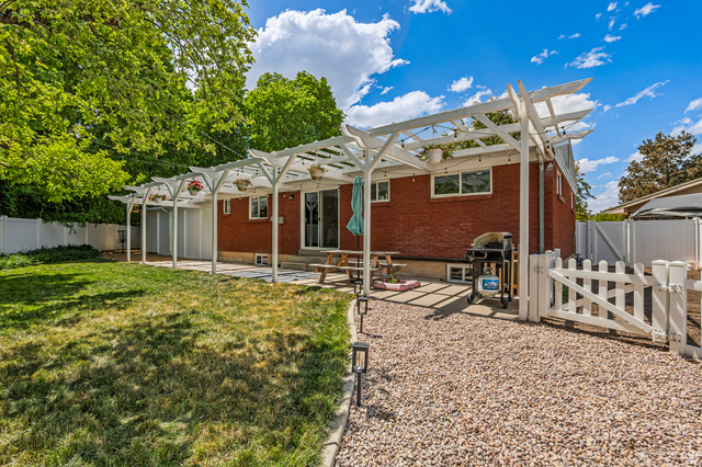 480 North 150 E Street Springville, UT 84663 - Photo 32 of 36 Expansive backyard featuring a partial grass lawn, a white pergola-covered patio with string lights, and a gravel area
