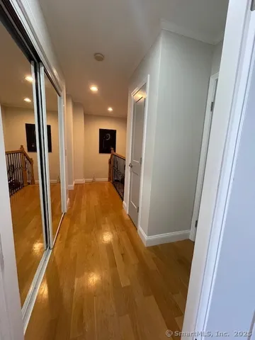 a view of a hallway to a livingroom with wooden floor and furniture