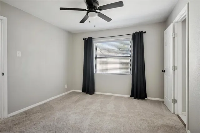 a view of a room with a ceiling fan and window