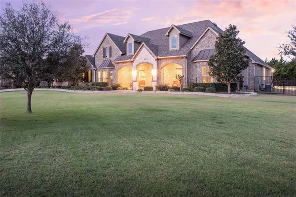 a view of a big house with a big yard and large trees
