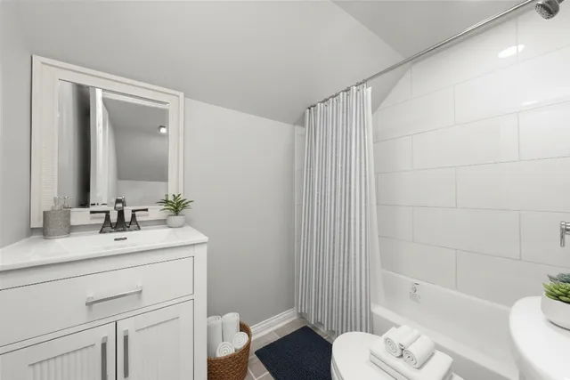 a bathroom with a toilet a sink a mirror a bathtub and vanity