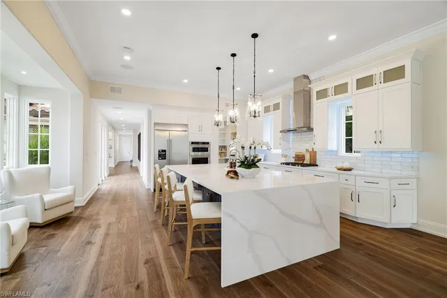 a kitchen with stainless steel appliances kitchen island granite countertop a stove a sink and white cabinets with wooden floor