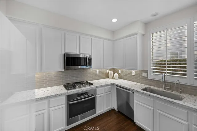 a kitchen with stainless steel appliances granite countertop a sink a stove a microwave and wooden cabinets