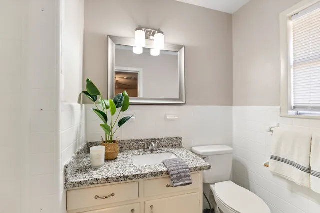 a bathroom with a granite countertop toilet sink and mirror