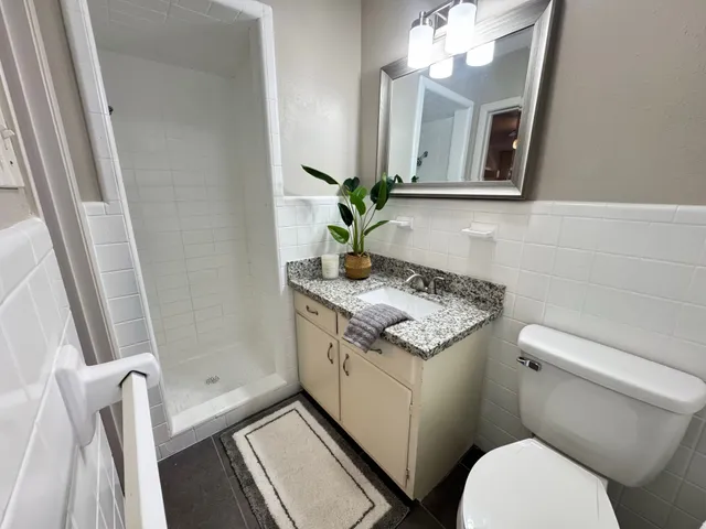 a bathroom with a granite countertop toilet sink and mirror