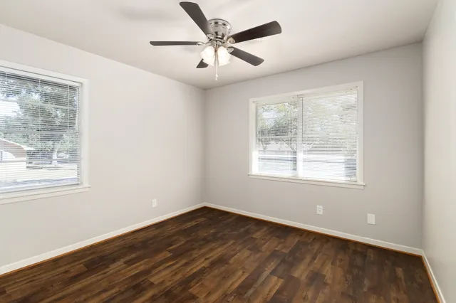 a view of an empty room with wooden floor and a window