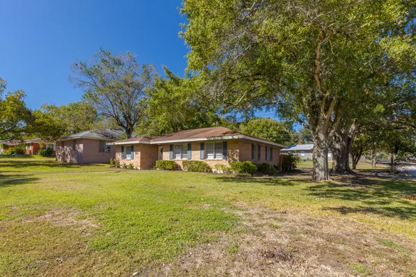 a yellow house sitting in middle of the middle of a yard