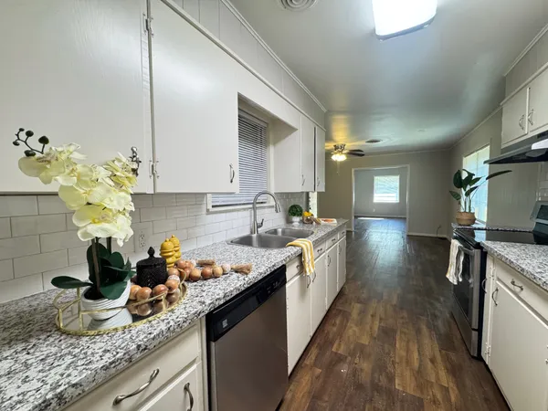 a kitchen with granite countertop a sink a stove and cabinets