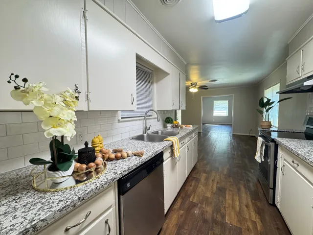a kitchen with granite countertop a sink a stove and cabinets