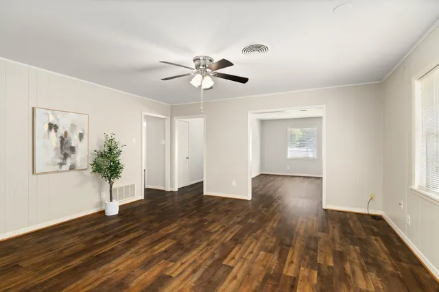 a view of an empty room with wooden floor and a window