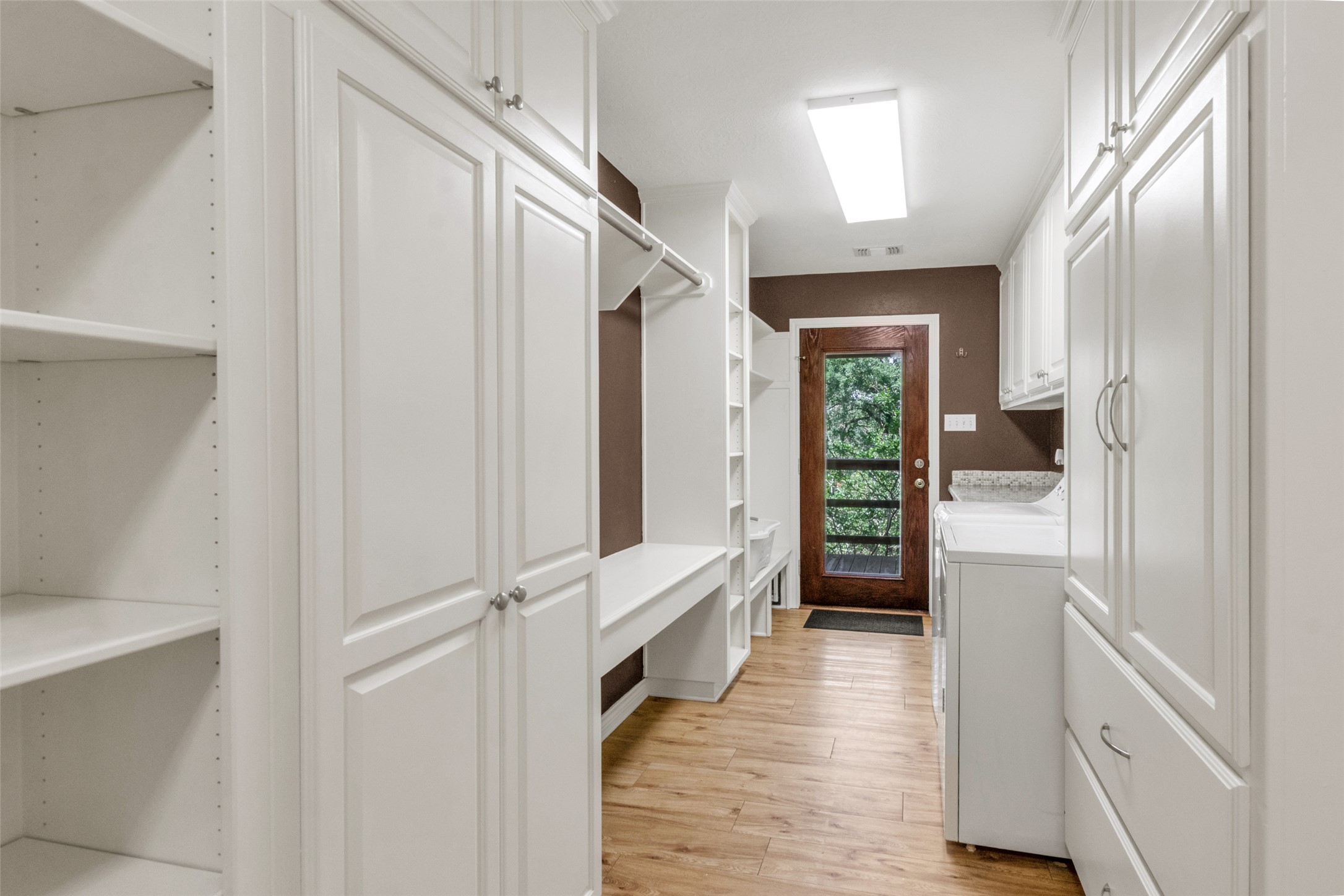 9997 Calhoun Road Bryan, TX 77808 - Photo 13 of 28 Ample built-in cabinetry and wood-look flooring define this highly functional utility space.