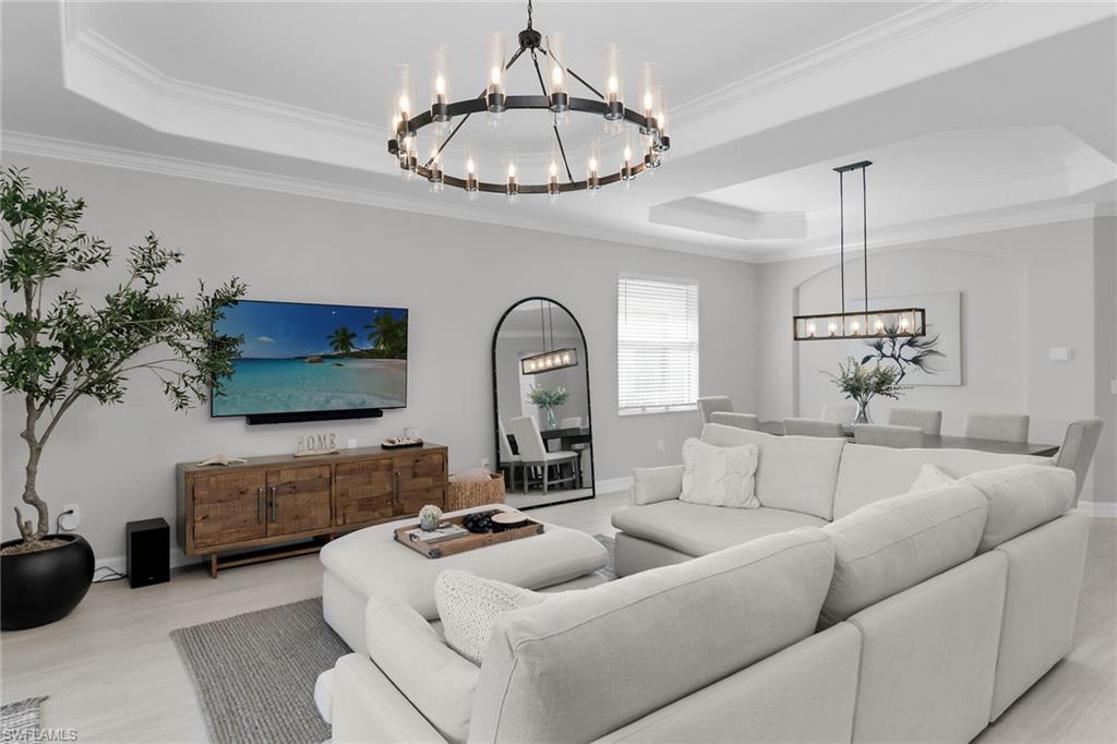 2926 Aviamar Circle Naples, FL 34114 - Photo 13 of 44 Living room featuring suspended lighting, a raised ceiling, wood finished floors, and crown molding