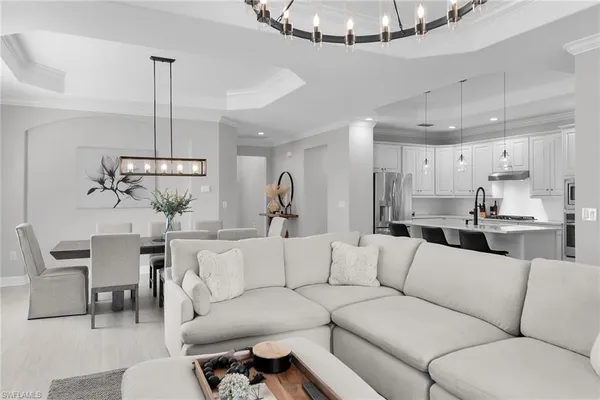a living room with furniture kitchen view and a chandelier
