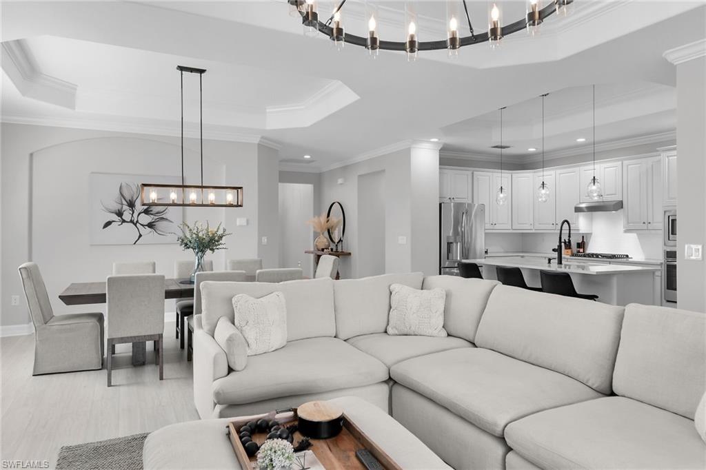 2926 Aviamar Circle Naples, FL 34114 - Photo 2 of 44 Living room featuring a tray ceiling, crown molding, suspended lighting, and light wood finished floors