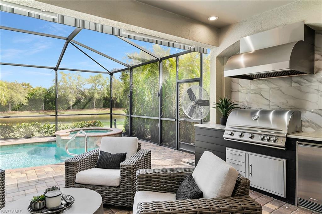 2926 Aviamar Circle Naples, FL 34114 - Photo 22 of 44 View of patio / terrace featuring area for grilling, glass enclosure, a sunroom, a pool with connected hot tub, and a water view