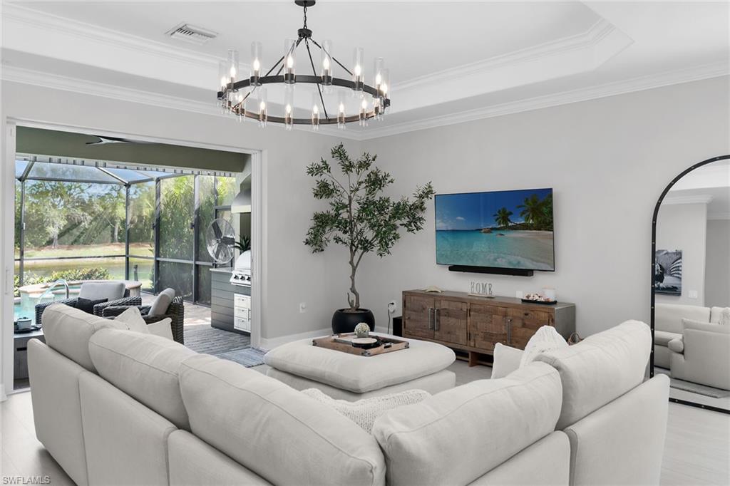 2926 Aviamar Circle Naples, FL 34114 - Photo 3 of 44 Living room featuring a sunroom, ornamental molding, a raised ceiling, and hanging lights