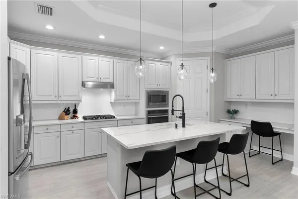 a kitchen with stainless steel appliances kitchen island granite countertop a table chairs sink and cabinets