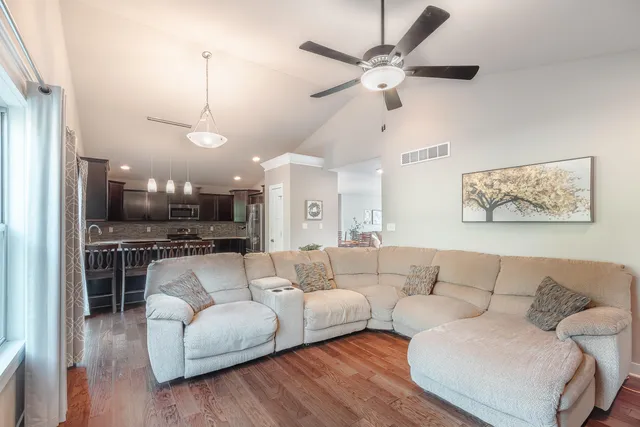 a living room with furniture kitchen view and a chandelier